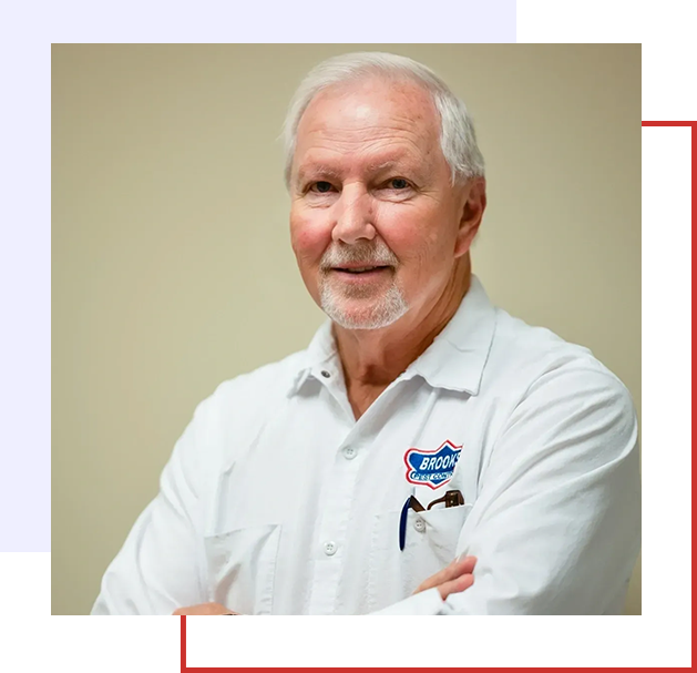 A man with his arms crossed wearing a white shirt.